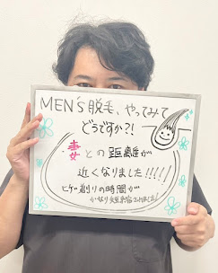 メンズ脱毛をやってみた感想を書いたボードを持つ男性